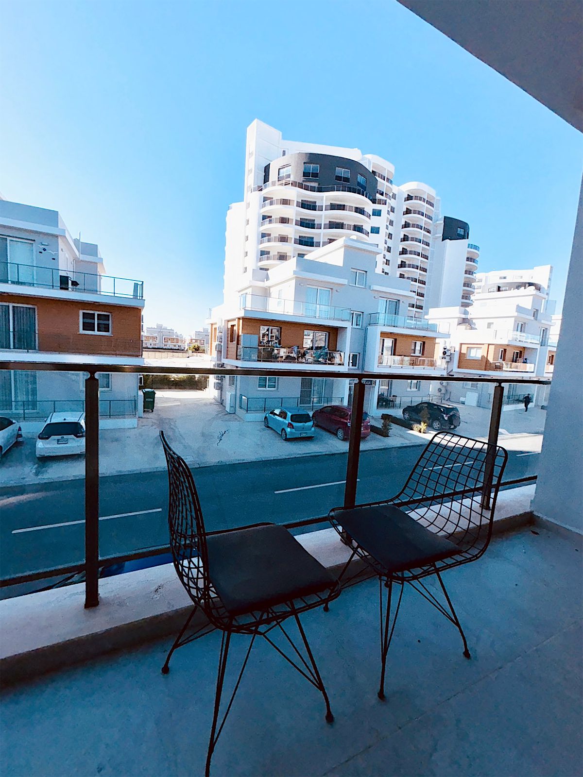 Royal studio balcony with two chairs, overlooking the street and neighbouring buildings